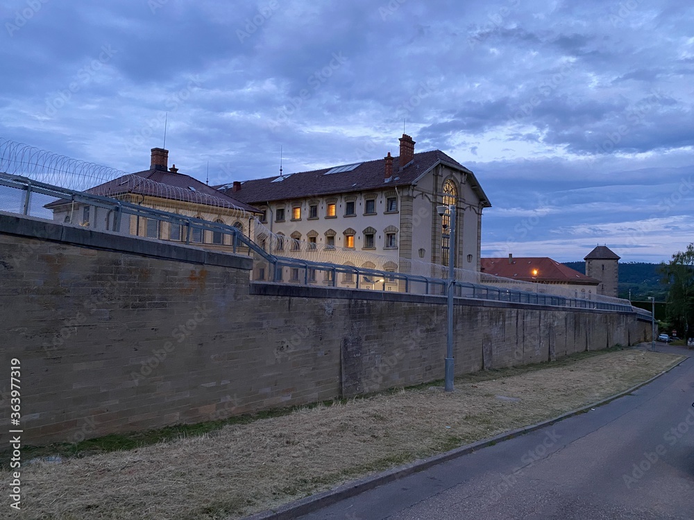 Gefängnisgebäude hinter dicken Mauer mit Stacheldraht zur blauen Stunde
