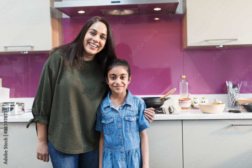 Portrait happy Indian mother and daughter cooking food in kitchen Portrait happy Indian mother and daughter cooking food in kitchen