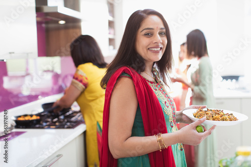 Portrait happy Indian woman in sari cooking food in kitchen