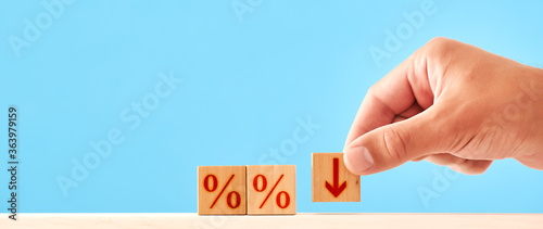 Fototapeta Naklejka Na Ścianę i Meble -  Percentage Down concept. man puts a wooden block with a down arrow next to blocks with percent symbols