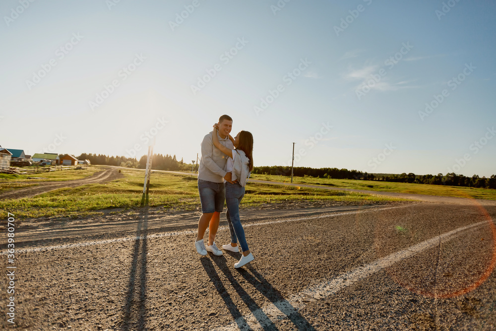 Portrait of a couple in love walking along the road. A man and a woman enjoy a vacation in the countryside. Young people walk in nature.