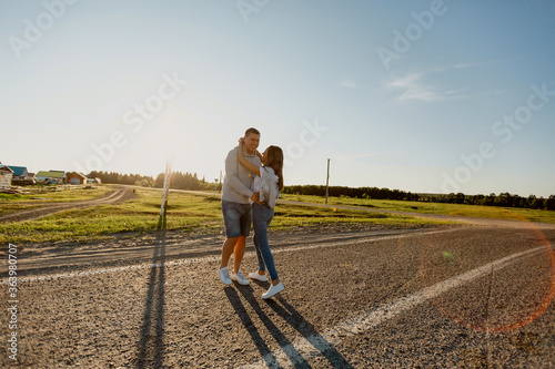 Portrait of a couple in love walking along the road. A man and a woman enjoy a vacation in the countryside. Young people walk in nature.