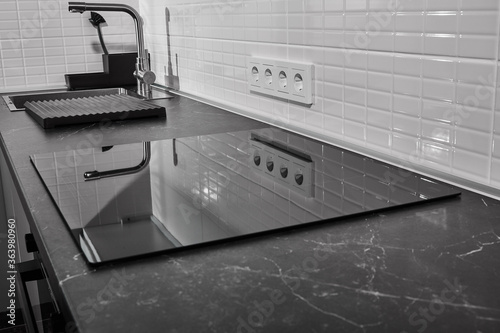 modern white kitchen with black countertop and induction hob photo