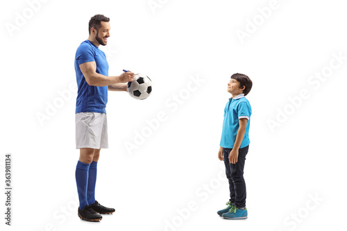 Footballer signing an autograph on a soccer ball for a boy fan