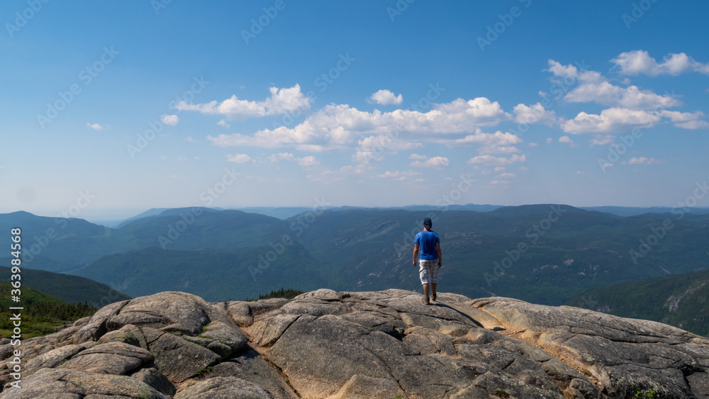 Young man standing on top of a mountain in the Grands-Jardins national park, Canada