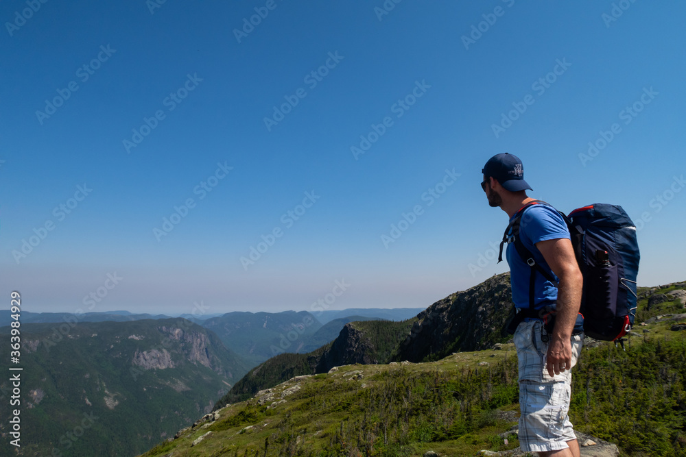 Young man standing at the top of a mountain in the Hautes-gorges-de-la-rivière-Malbaie national park, Canada 