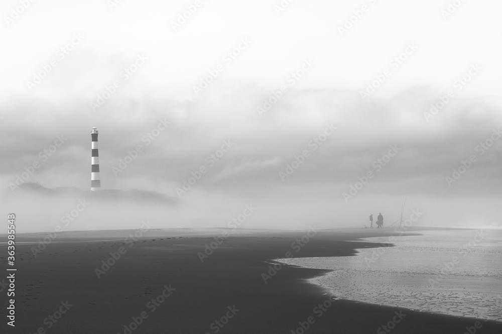 fishermen in front of the lighthouse in the foggy morning. 