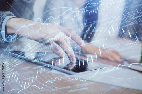 Double exposure of forex graph drawing and man and woman working together holding and using a mobile device. Trade concept.