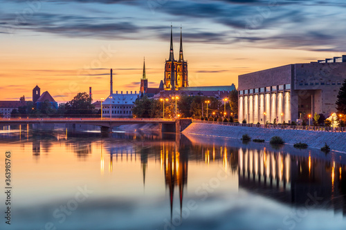 Famous historic two towers of Wroclaw Cathedral of St. John the Baptist. Beautiful view on Oder river and illuminated city architecture. Beautiful sky, light reflections on blurred water