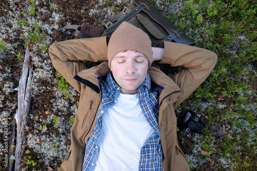 Restful young man laying down on the ground of a forest