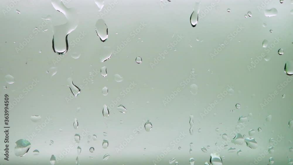 Extreme closeup of water drops on transparent glass, raindrops falling on window