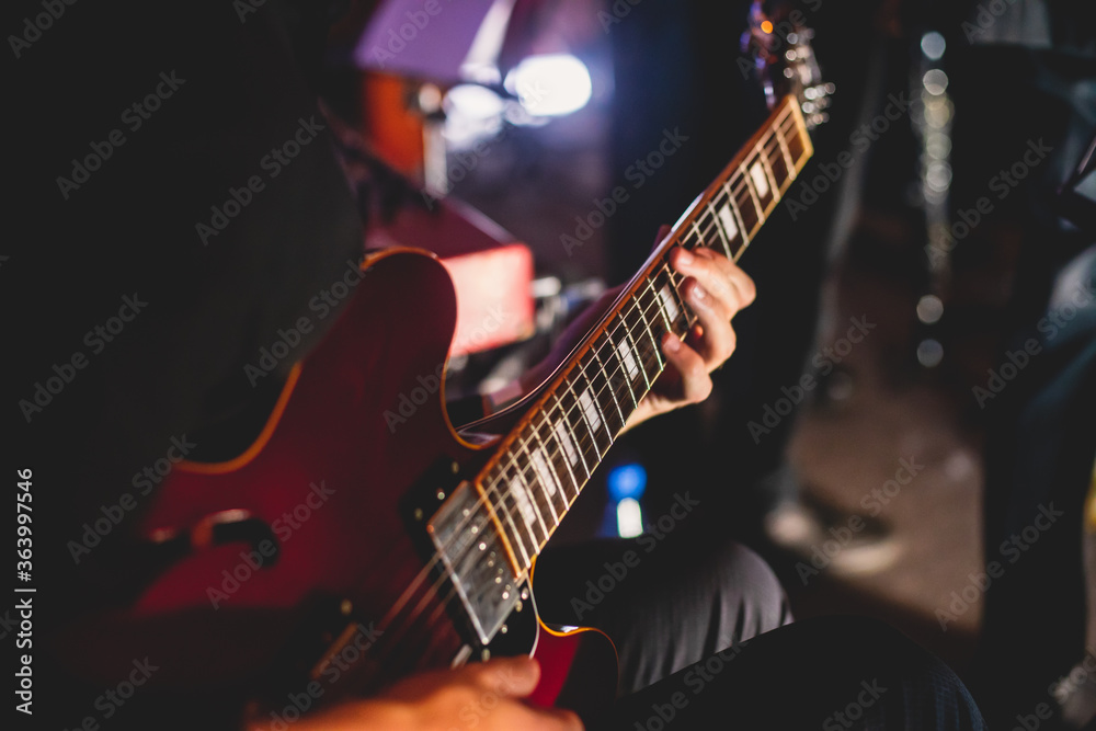 Obraz premium Concert view of an electric guitar player with vocalist and musical band in the background