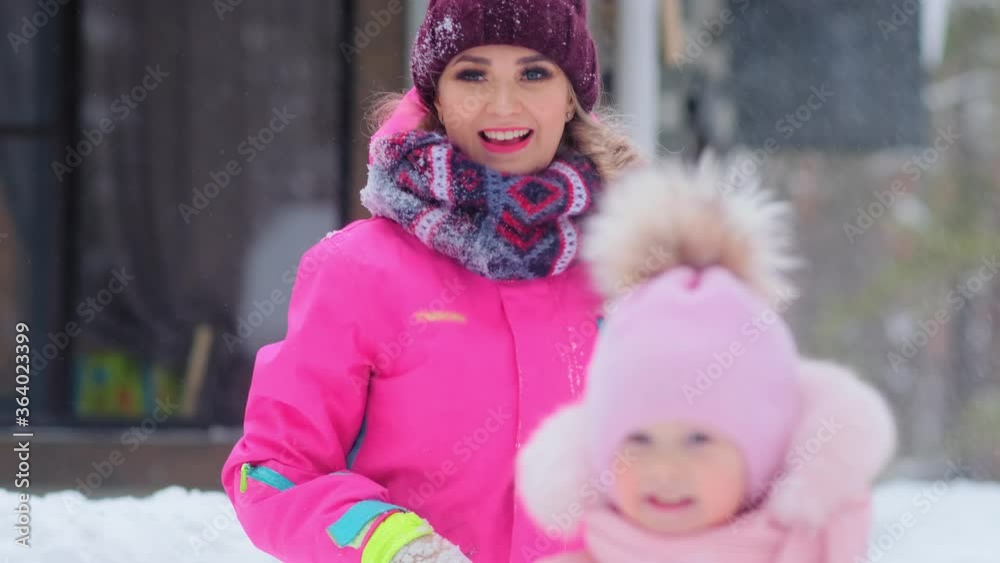 woman throws snowball with laughter and little daughter smiles standing against building slow motion woman throws snowball with laughter and little daughter smiles standing against building slow motion