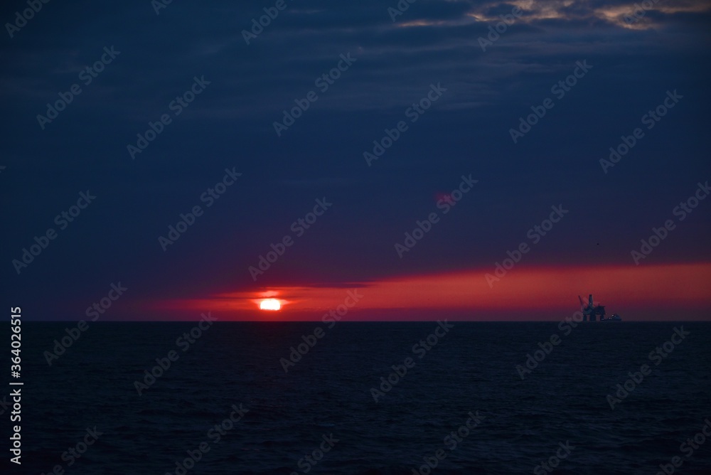 Autumn red sunset over the cold polar sea. Red clouds, illuminated by the cold sun, over the horizon. Photo from the side of the ship.