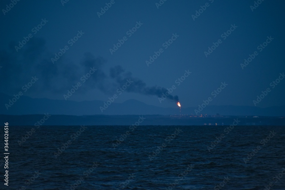 A huge torch from a gas processing plant burns in the night sky over Sakhalin Island. Extraction of hydrocarbons. Pollution of the planet. A huge torch from a gas processing plant burns in the night sky over Sakhalin Island. Extraction of hydrocarbons. Pollution of the planet.