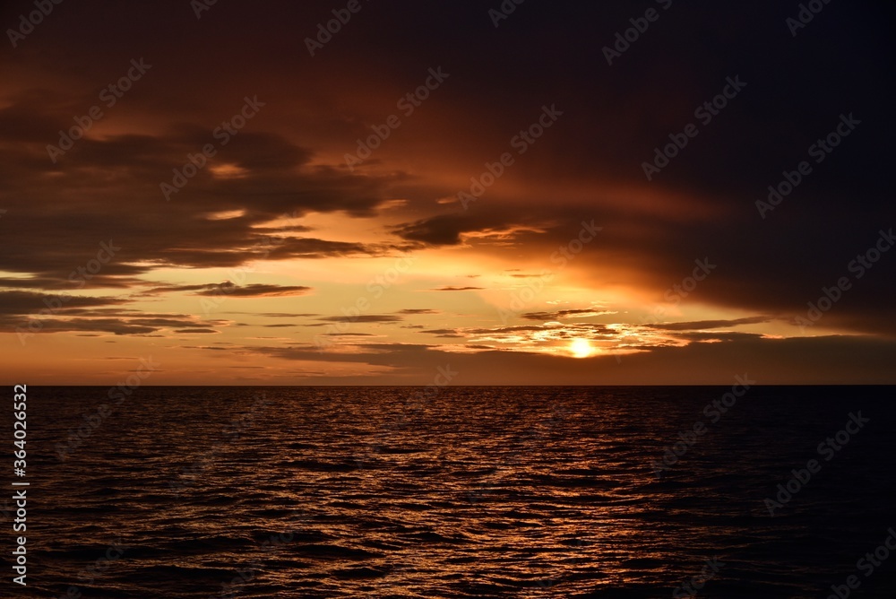 Obraz premium Autumn red sunset over the cold polar sea. Red clouds, illuminated by the cold sun, over the horizon. Photo from the side of the ship.