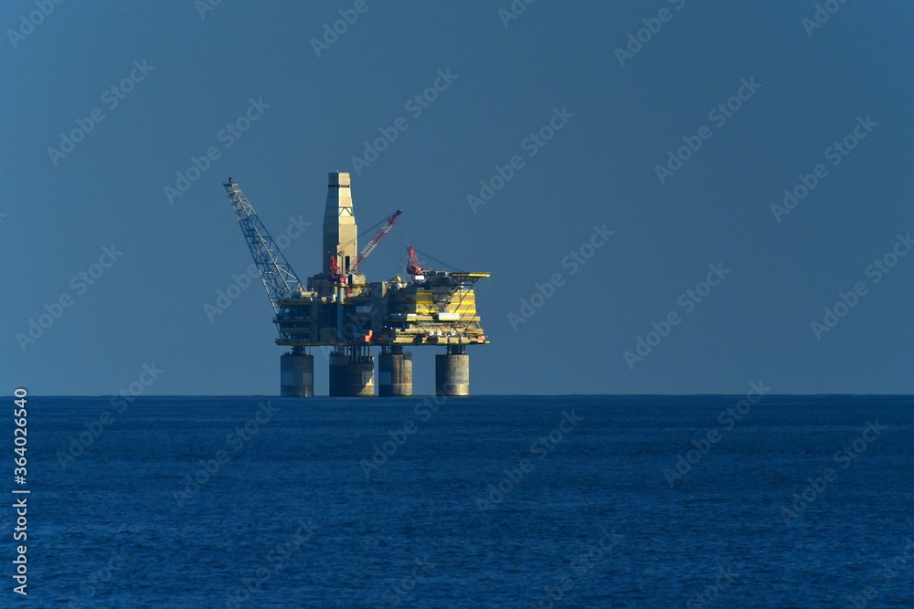 Drilling platform at sea. Extraction of minerals on the shelf. A huge red platform rises above the water. Early morning. Hydrocarbon energy. 