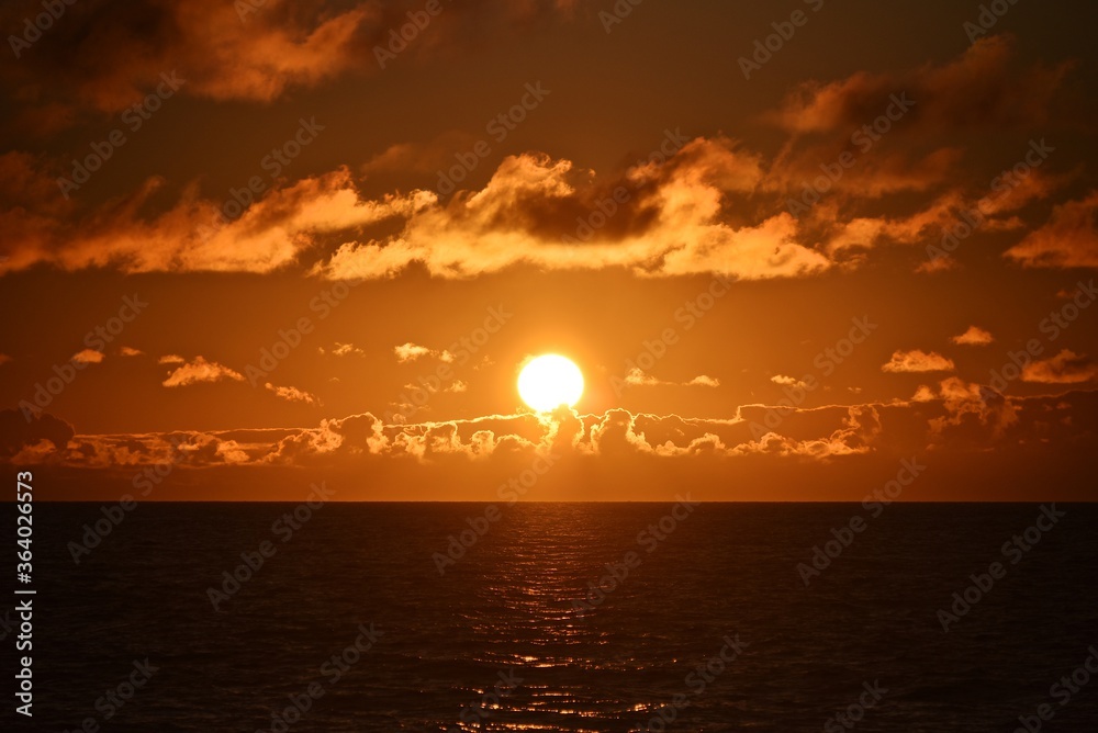 Golden sunset in the Sea of Okhotsk. The sun's rays are breaking through the clouds. Blue autumn sky. Seascape.
