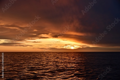 Autumn red sunset over the cold polar sea. Red clouds, illuminated by the cold sun, over the horizon. Photo from the side of the ship.