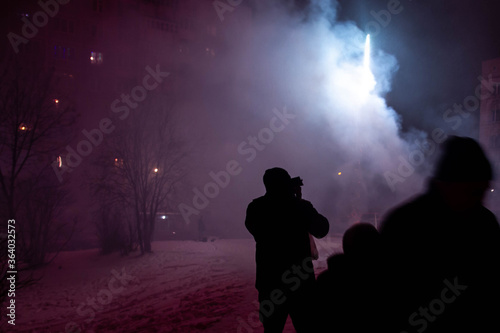People watch the launch of small fireworks in the winter on the street. New year and Christmas celebrations in Russia. Traditions of digging and setting off fireworks.