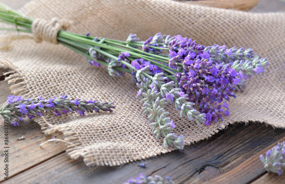 bouquet of lavender flowers on piece of fabric on  wooden background - obrazy, fototapety, plakaty 