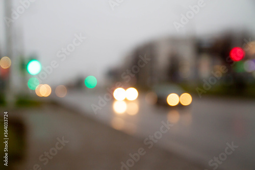 Traffic traffic in the town. Green traffic light. Cars go on the road. Blurred image. Wet road after rain.