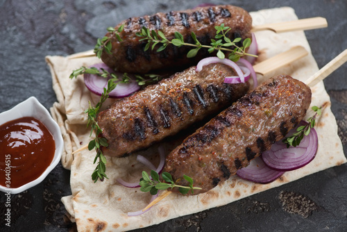 Close-up of grilled lula-kebabs made of beef meat and served with lavash flatbread, studio shot