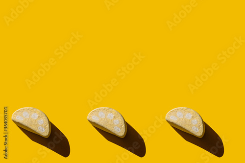 Several tasty marshmallows with hard shadows on a yellow background with copy space