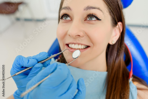 Dentist hands with dental instruments examination patient's teeth in medical clinic