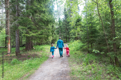 father with two kids walk in forest, family hiking in nature