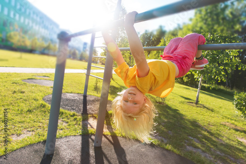 Photography happy cute little girl upside down on monkey bars