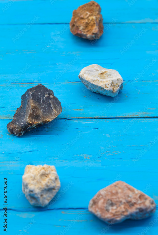 Five natural stones of different shapes lie on a blue wooden background close-up Five natural stones of different shapes lie on a blue wooden background close-up