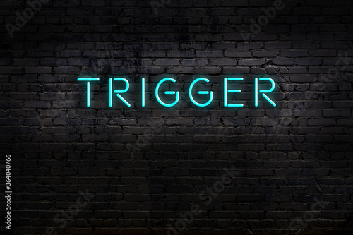 Neon sign. Word trigger against brick wall. Night view