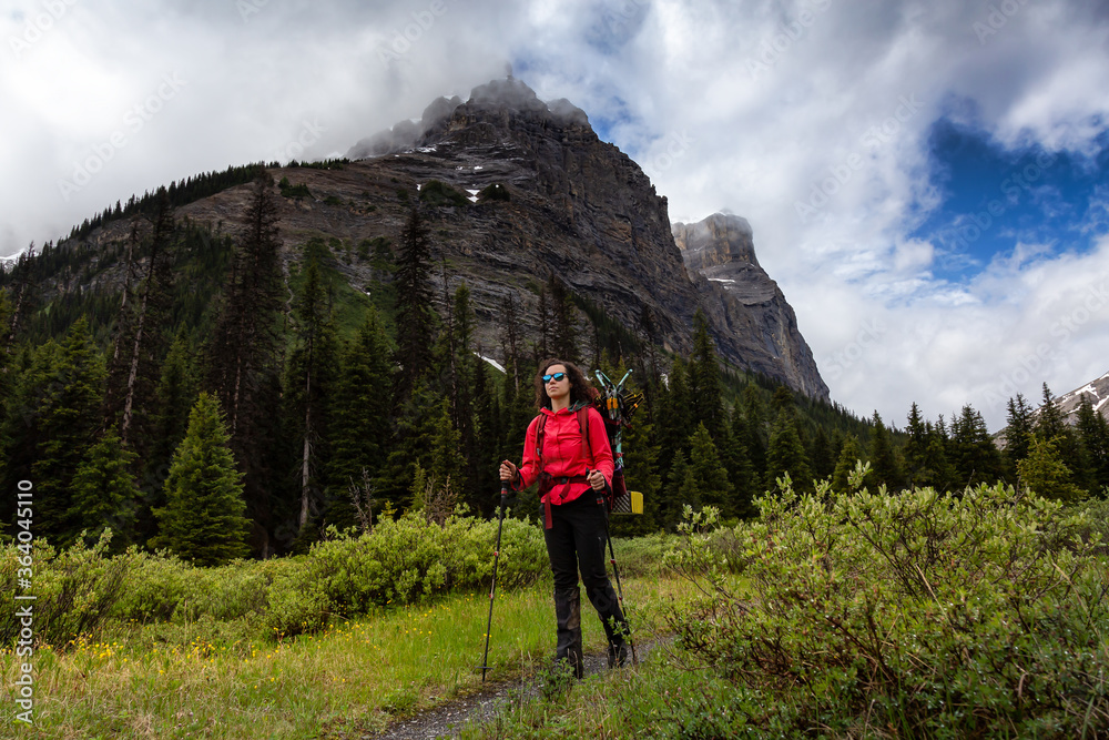 Female Backpacker Hiking in Canadian Rockies during a cloudy day. Taken near Banff, boarder of British Columbia and Alberta, Canada. Concept: Explore, Adventure, Trekking, Backpacking