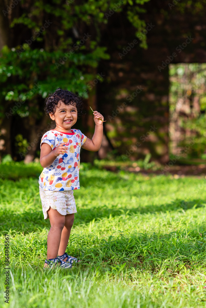 Playful Pretty Indian girl child/infant playing outdoors with nice environmental background Playful Pretty Indian girl child/infant playing outdoors with nice environmental background