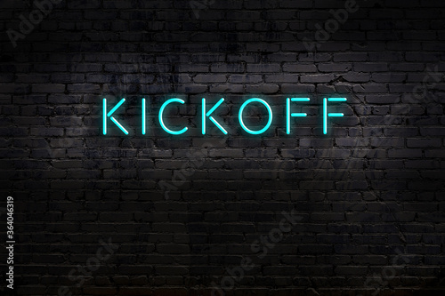 Neon sign. Word kickoff against brick wall. Night view