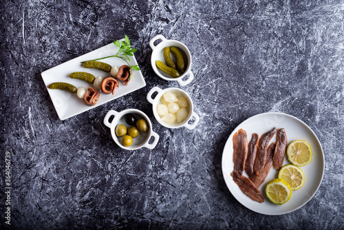 anchovy onion and gherkin skewers on a plate surrounded by ingredients