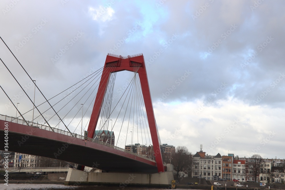 Fototapeta premium Red steel bridge over river Nieuwe Maas named Willemsbrug in Rotterdam.
