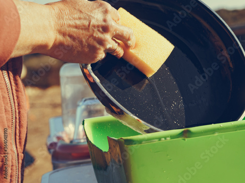 Woman washing dishes in bowl, capming outdoor photo