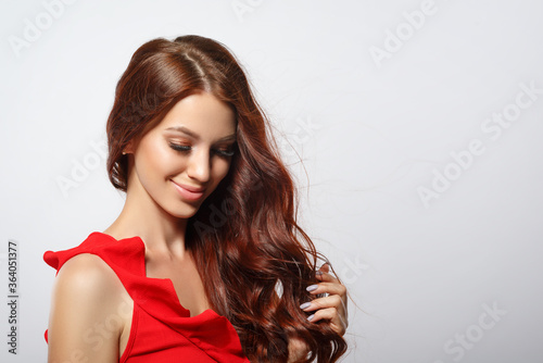 Studio glamor portrait of a beautiful woman with luxurious hair on a light background.