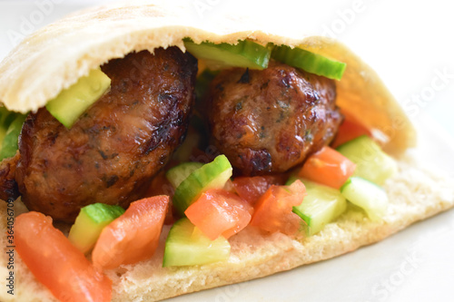 Sheftalia Cypriot Sausages with Fresh Vegetables (Cucumber and Tomato) on a White Plate. Traditional Cypriot food: Cypriot Lamb and Pork Sausages.  Copy space is on the blurry part. Selective focus.