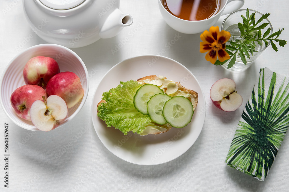 Breakfast in a white bowl on a light background croissant with herbs, vegetables, butter, cheese, herbal, green tea, flower, fruit, yogurt