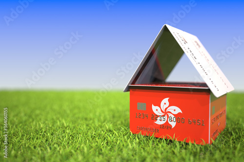 National flag of Hong Kong on credit card house in the grass. Home loans related 3D rendering