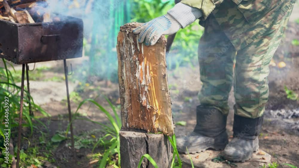 Mature man chopping wood on log outdoor. Close up of men's hands cutting wood with axe in garden. Mature man chopping wood on log outdoor. Close up of men's hands cutting wood with axe in garden.