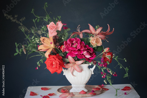 bouquet of summer flowers in vase on vintage white wooden shelf on dark background photo