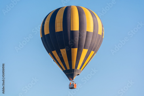 Balloon flying high in the sky. Balloon basket with people. Aeronautic sport. Burning gas. Bright multi-colored balloon. Romantic trip. Free space for text.