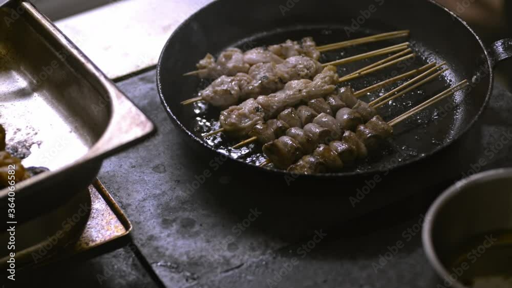 Process of cooking fried meat in hot pan at restaurant kitchen irrl. Appetizing pieces on sticks are frying on metal surface with oil on stove in room. Preparation of delicious non-healthy foods Process of cooking fried meat in hot pan at restaurant kitchen irrl. Appetizing pieces on sticks are frying on metal surface with oil on stove in room. Preparation of delicious non-healthy foods