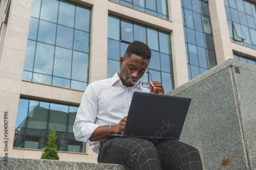 Feeling exhausted. Frustrated young black african man keeping eyes closed and looking tired from extra working on laptop