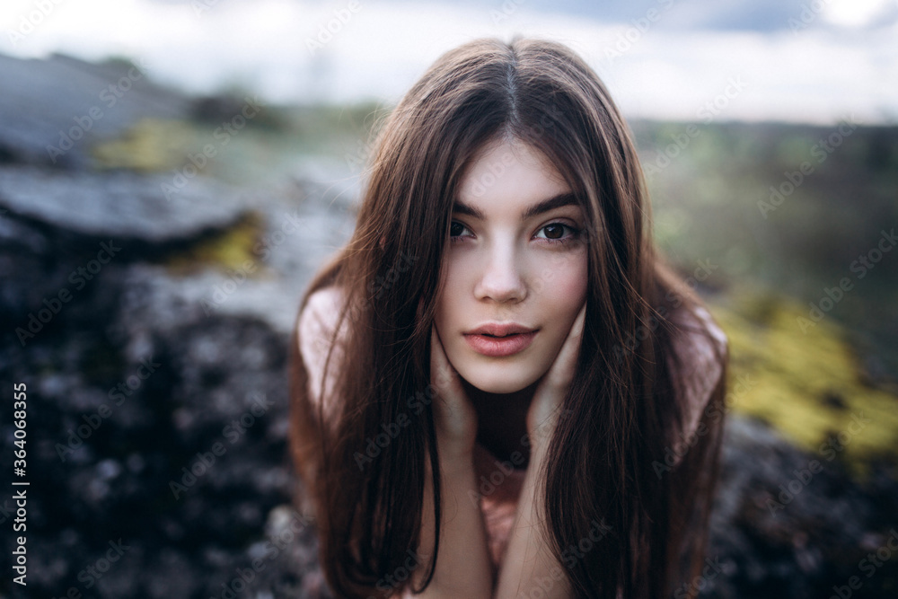 Young brunette girl portrait outdoors in grey mountains outdoors. Woman beauty concept Young brunette girl portrait outdoors in grey mountains outdoors. Woman beauty concept