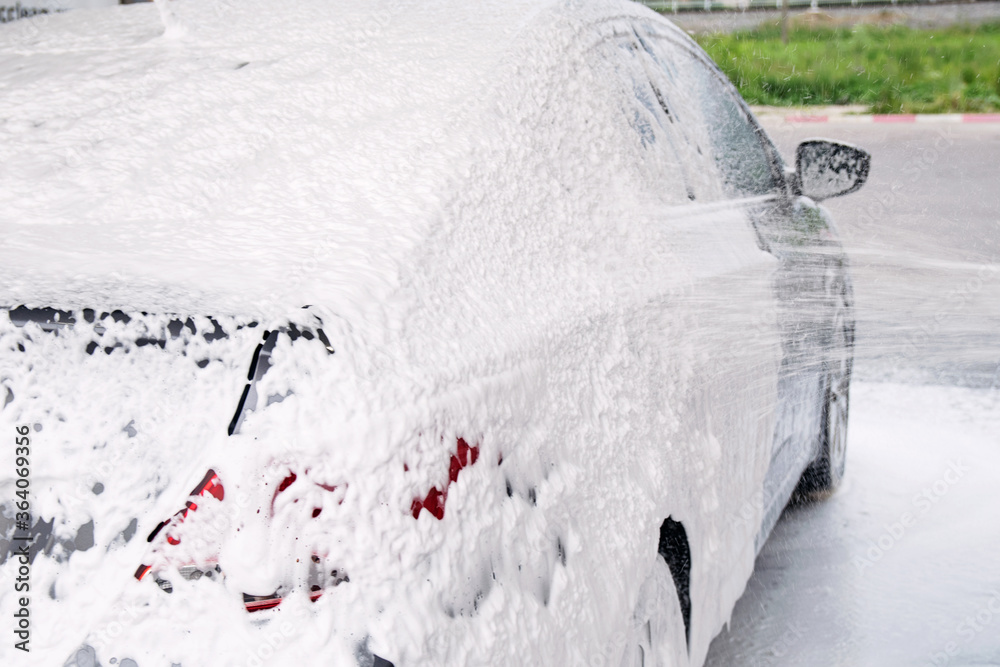 gray cars are washed through a gun with detergent at the sink